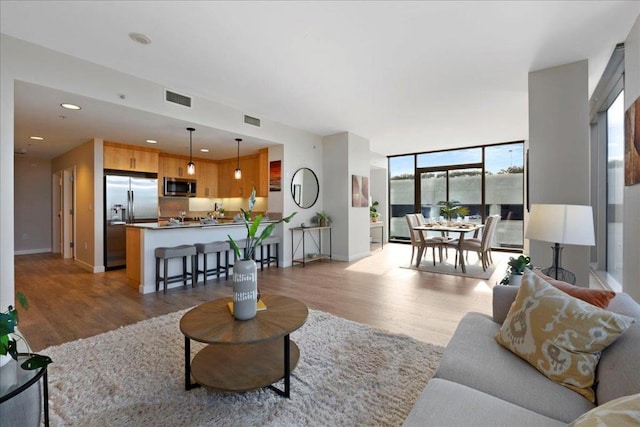 living room with light wood-type flooring and floor to ceiling windows