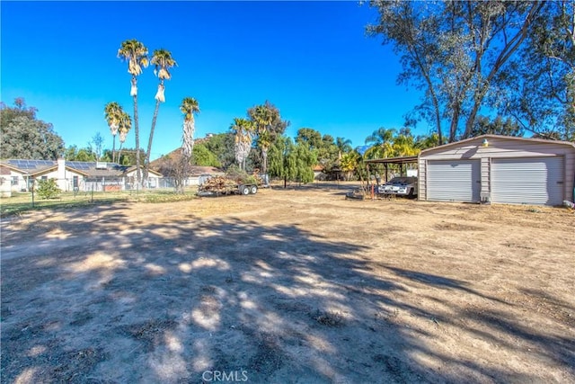 view of yard featuring a garage, an outdoor structure, and a carport