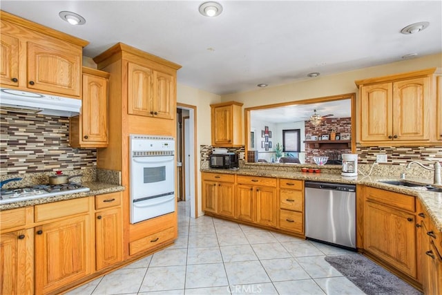 kitchen featuring tasteful backsplash, sink, white appliances, and light stone countertops