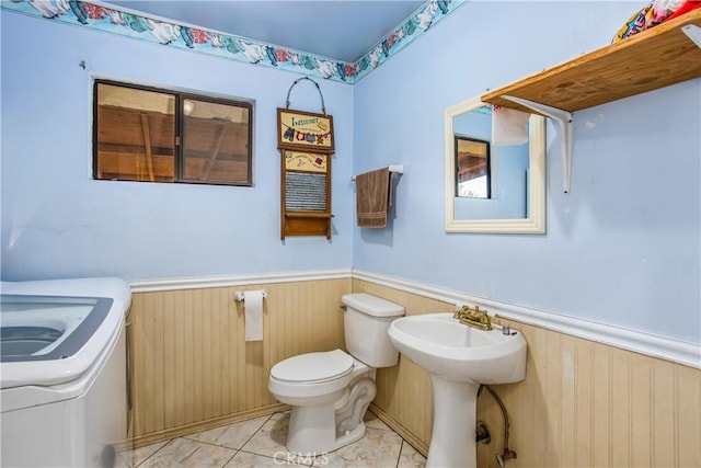 bathroom with washer / clothes dryer, tile patterned flooring, wood walls, and toilet