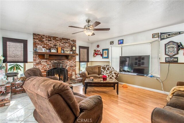 living room featuring ceiling fan, a textured ceiling, and a fireplace