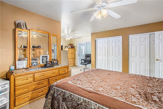 carpeted bedroom featuring multiple closets and ceiling fan