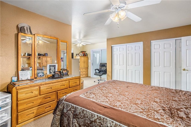 carpeted bedroom with two closets and ceiling fan