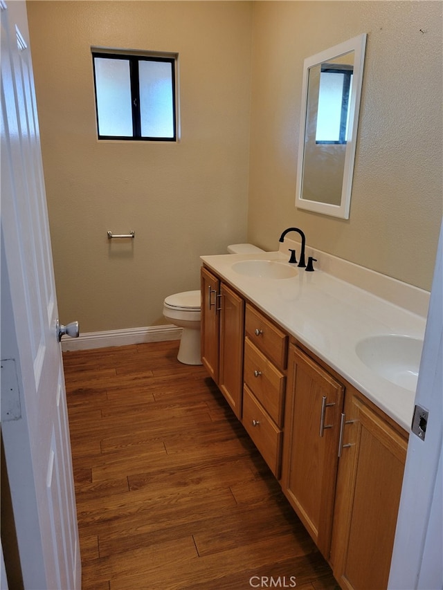 bathroom featuring wood-type flooring, toilet, and vanity