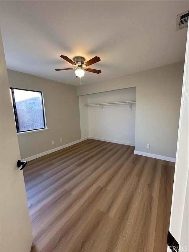 unfurnished bedroom featuring ceiling fan, a closet, and wood-type flooring