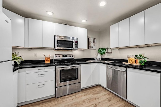 kitchen with sink, light wood-type flooring, appliances with stainless steel finishes, and white cabinetry