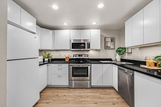 kitchen featuring stainless steel appliances, white cabinets, sink, and light wood-type flooring