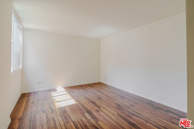 unfurnished room with a healthy amount of sunlight and dark wood-type flooring