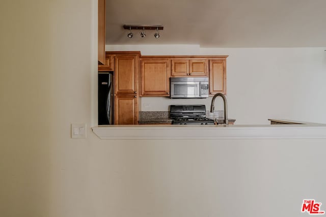 kitchen featuring black refrigerator, rail lighting, sink, and range