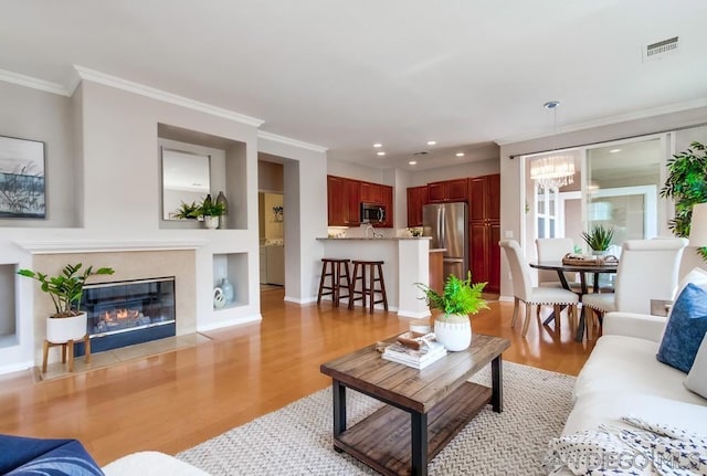 living room featuring light wood-type flooring, a notable chandelier, and crown molding