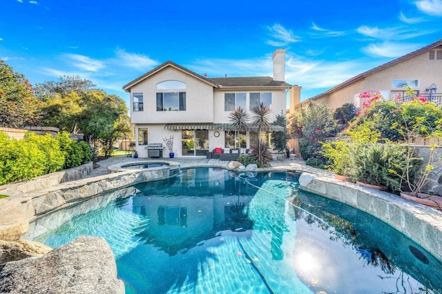 rear view of property with a swimming pool with hot tub and a patio area