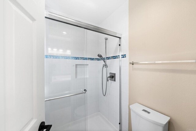 bathroom featuring toilet and an enclosed shower