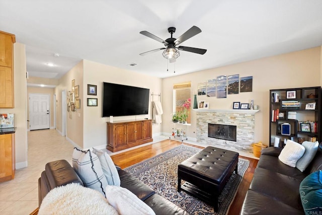 tiled living room with a fireplace and ceiling fan