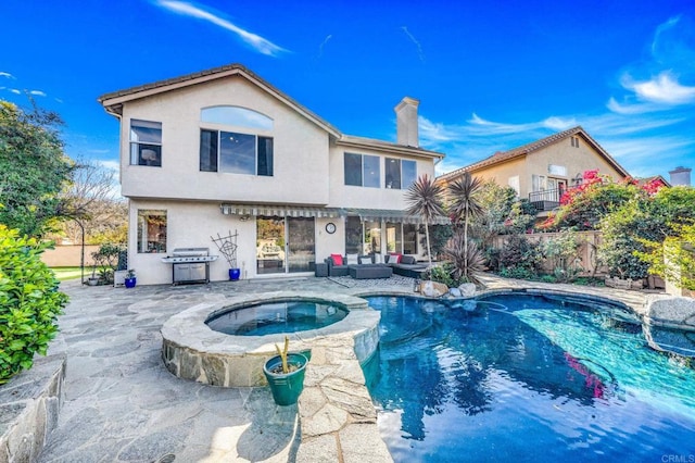 rear view of property with a swimming pool with hot tub and a patio area