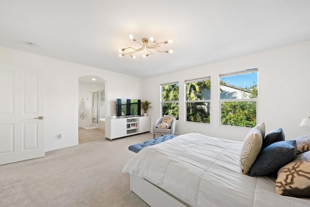 bedroom with ensuite bath, an inviting chandelier, and light carpet