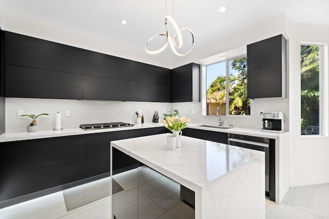 kitchen with sink, stainless steel appliances, decorative light fixtures, backsplash, and a kitchen island