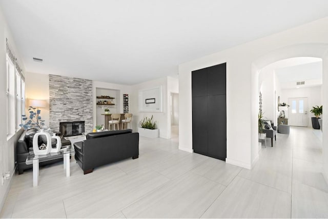 living room with a large fireplace, built in features, and light tile patterned flooring