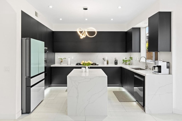 kitchen with sink, fridge, light stone counters, and a center island