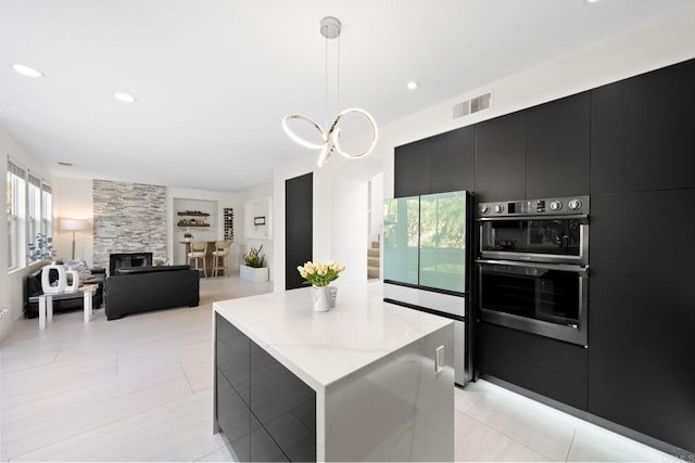 kitchen featuring a center island, multiple ovens, double oven, pendant lighting, and built in shelves