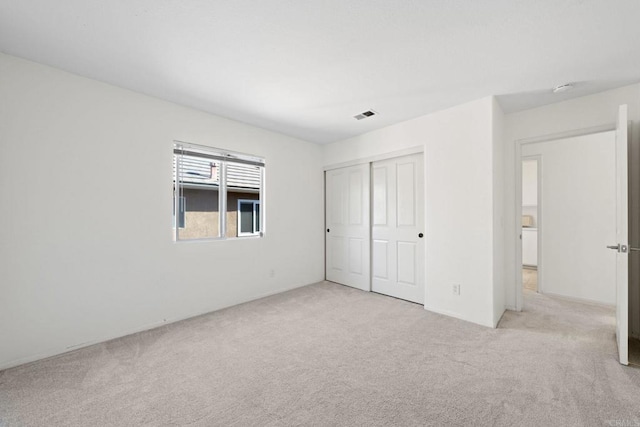 unfurnished bedroom featuring a closet and light carpet