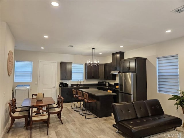 kitchen with stainless steel fridge with ice dispenser, a breakfast bar, pendant lighting, a kitchen island, and sink