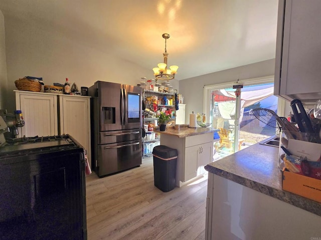 kitchen with stainless steel refrigerator with ice dispenser, hanging light fixtures, light wood-type flooring, white cabinets, and range