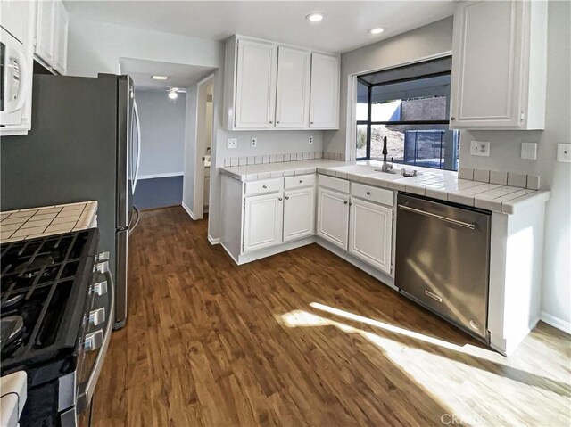 kitchen with stainless steel appliances, white cabinets, tile countertops, and dark hardwood / wood-style floors