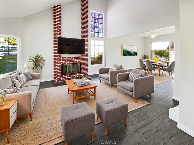 living room featuring a high ceiling, a fireplace, ceiling fan, and a wealth of natural light