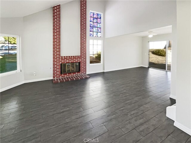 unfurnished living room featuring a brick fireplace, high vaulted ceiling, and ceiling fan