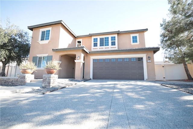 traditional-style home featuring fence, an attached garage, concrete driveway, stucco siding, and a tiled roof