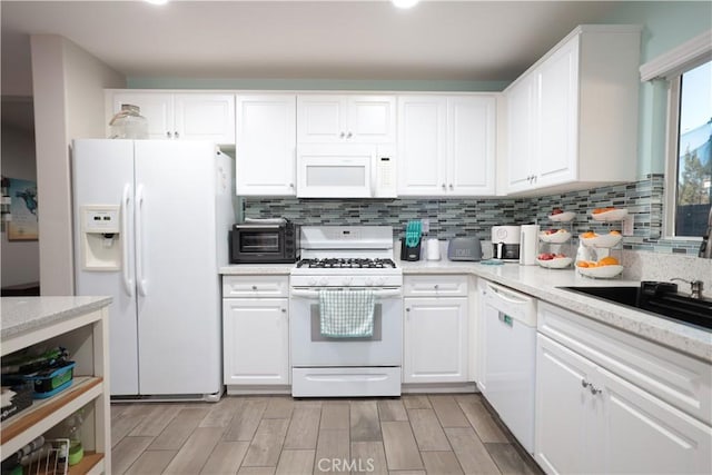 kitchen with light wood-type flooring, white cabinetry, tasteful backsplash, and white appliances