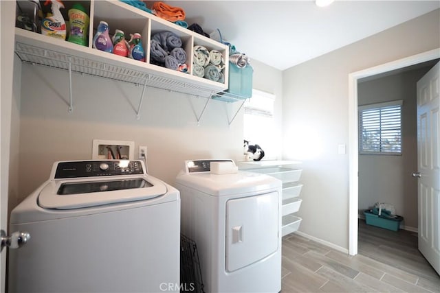 washroom with a healthy amount of sunlight, light wood-style floors, washing machine and dryer, and laundry area