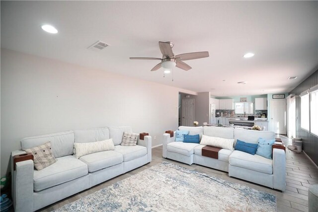 living area with light wood-style floors, ceiling fan, visible vents, and recessed lighting