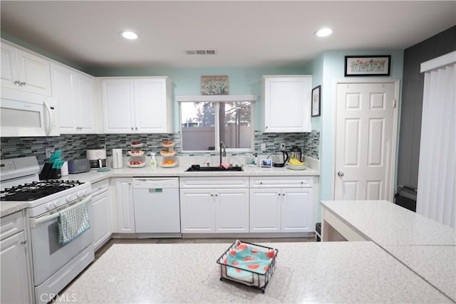 kitchen with sink, white cabinets, white appliances, and decorative backsplash