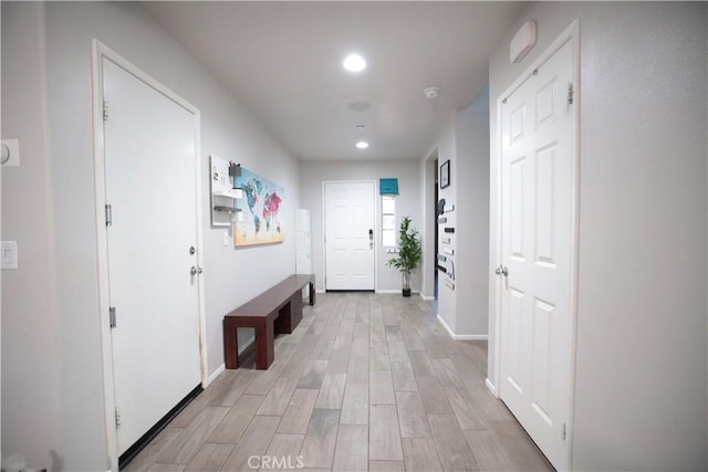 hallway featuring baseboards, recessed lighting, and light wood-type flooring