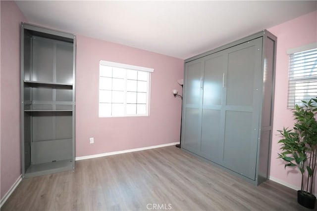 unfurnished bedroom featuring baseboards, a closet, and light wood-style flooring