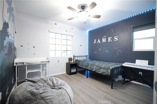 bedroom featuring multiple windows, a ceiling fan, wood finished floors, and baseboards