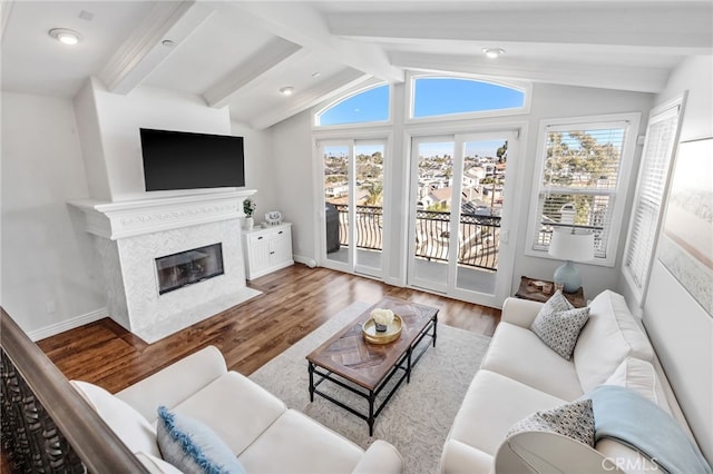 living room featuring hardwood / wood-style floors, a high end fireplace, a healthy amount of sunlight, and vaulted ceiling with beams