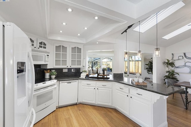 kitchen with white appliances, kitchen peninsula, tasteful backsplash, a tray ceiling, and white cabinets