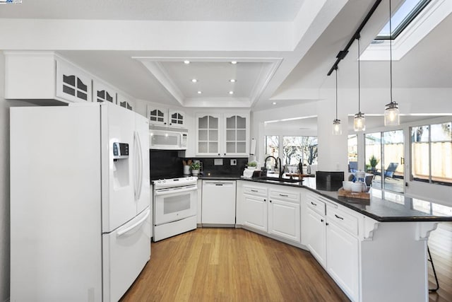 kitchen with white appliances, hanging light fixtures, a tray ceiling, white cabinets, and sink