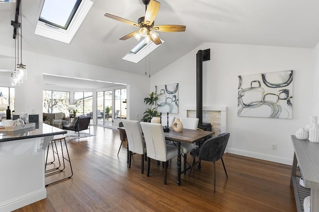 dining space featuring ceiling fan, dark hardwood / wood-style flooring, lofted ceiling, and a wood stove