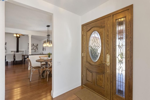 foyer with lofted ceiling, an inviting chandelier, decorative columns, and hardwood / wood-style flooring