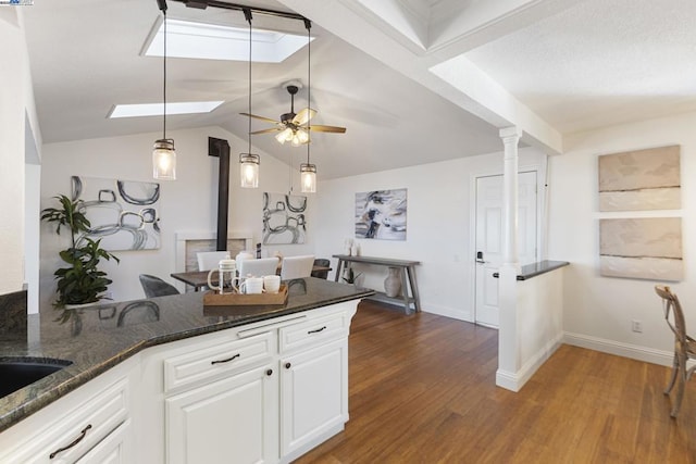 kitchen with white cabinets, dark stone countertops, ceiling fan, kitchen peninsula, and dark hardwood / wood-style flooring