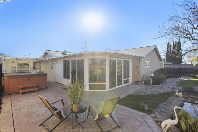 back of property featuring a sunroom, a patio area, and a hot tub