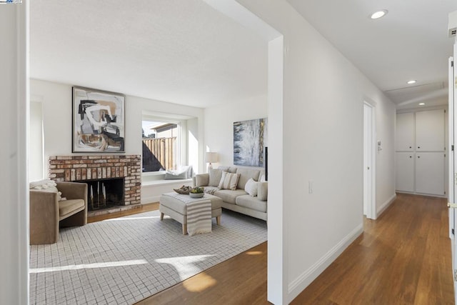 living room with a brick fireplace and wood-type flooring