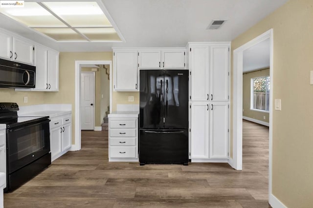 kitchen featuring black appliances, white cabinets, and wood-type flooring