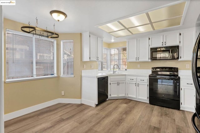 kitchen featuring sink, white cabinetry, light wood-type flooring, and black appliances