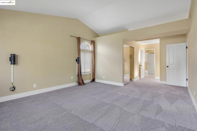 spare room with vaulted ceiling and light colored carpet