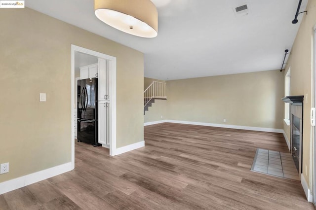 unfurnished living room featuring hardwood / wood-style flooring and a tiled fireplace