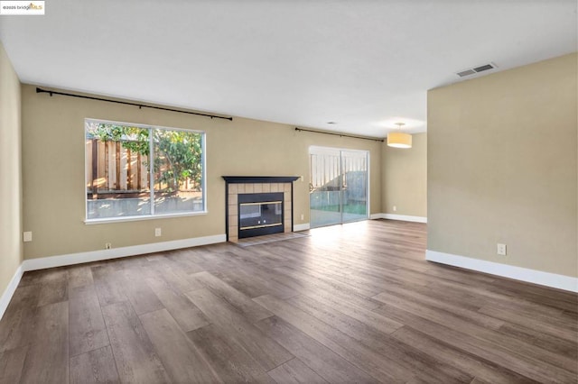 unfurnished living room featuring plenty of natural light, a fireplace, and wood-type flooring